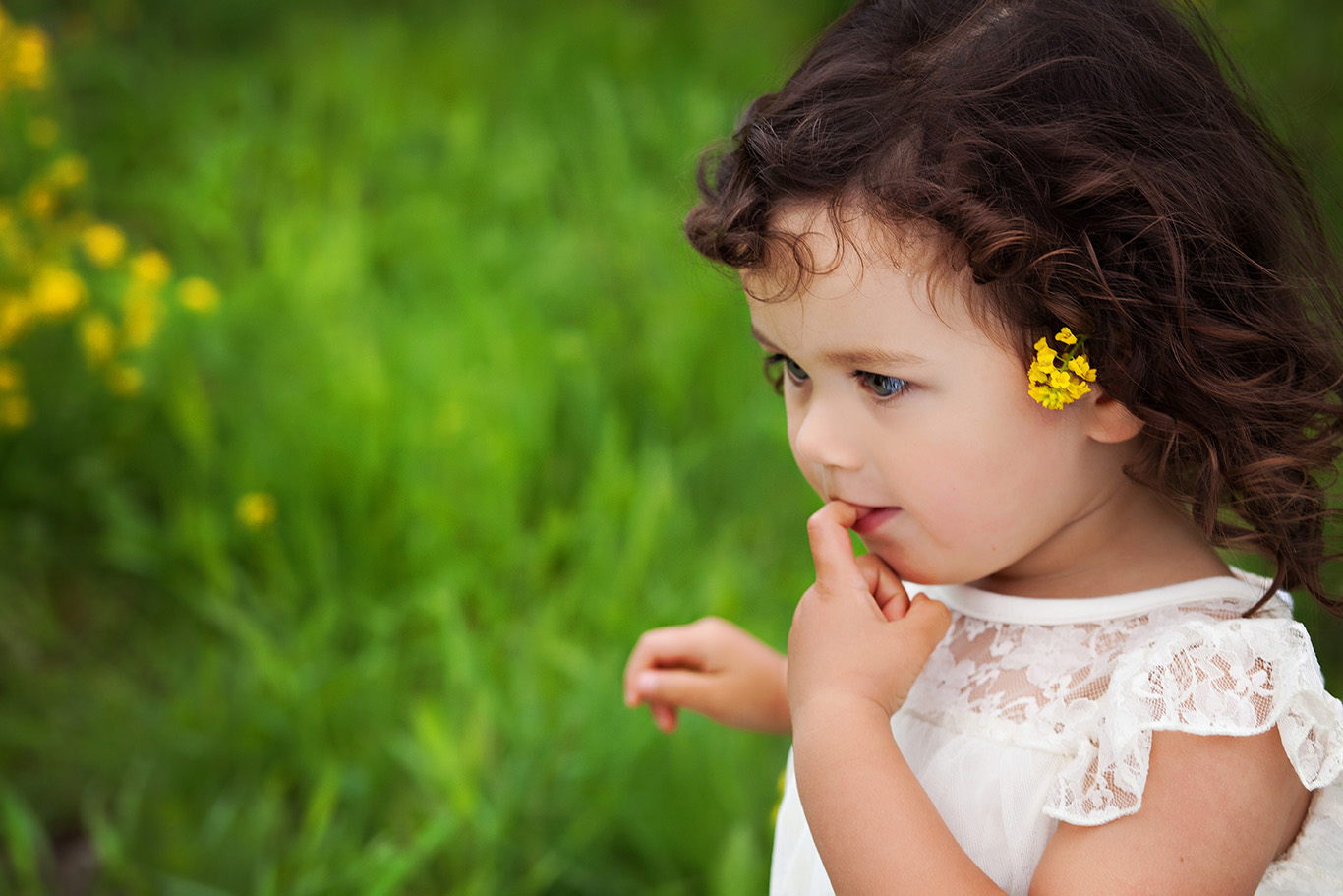 Little girl walking through a field of spring flowers with a flower in her hair