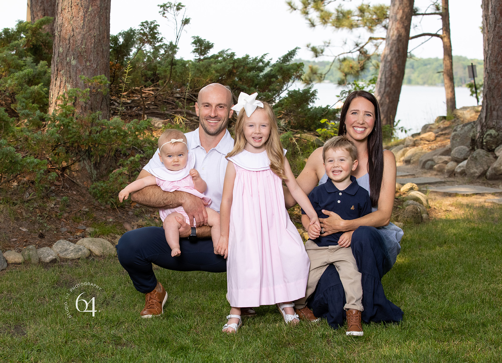 Young family of Five dressed up posing outdoors in front of a lake setting