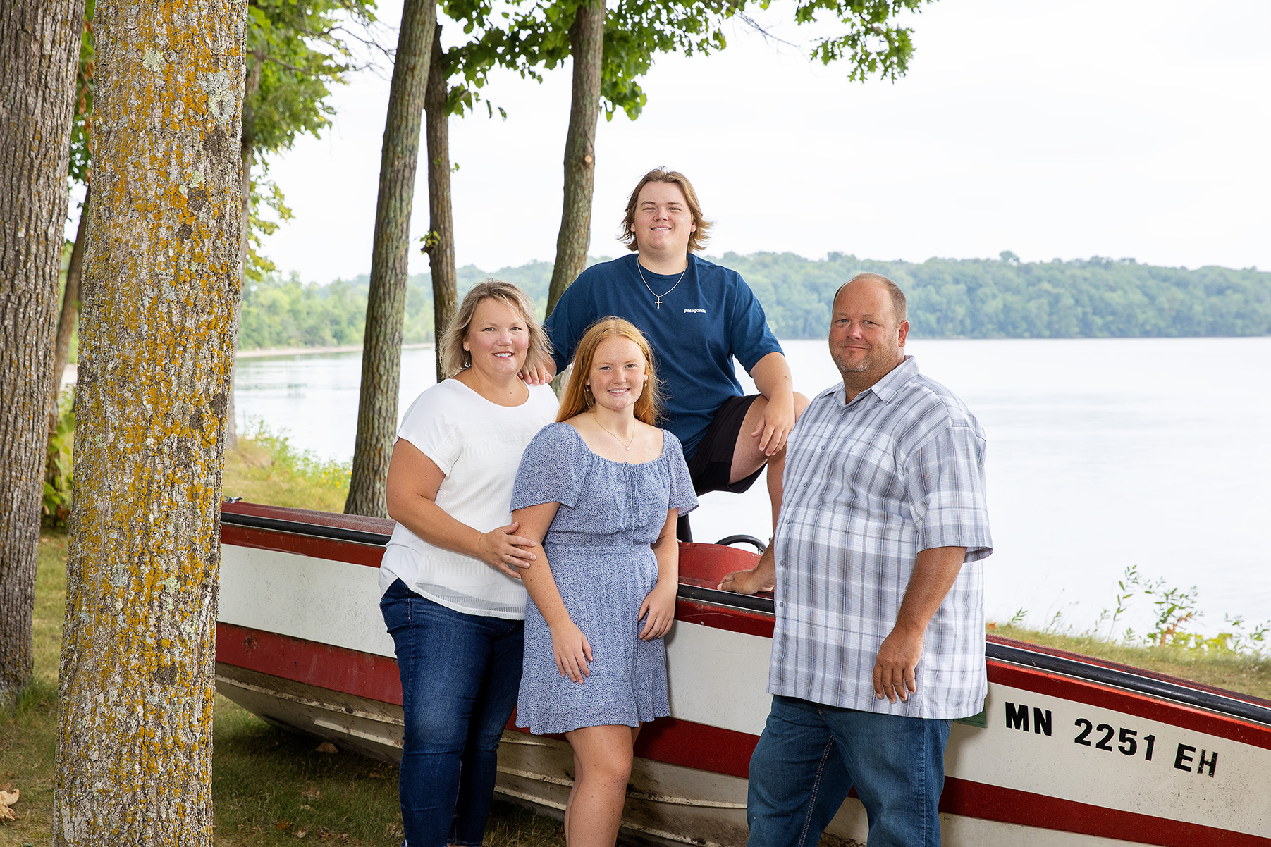 Family of four posing in front of a broken down boat with leech lake in the background