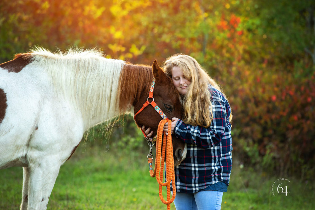 Young woman with her horse outdoors with bright fall colors